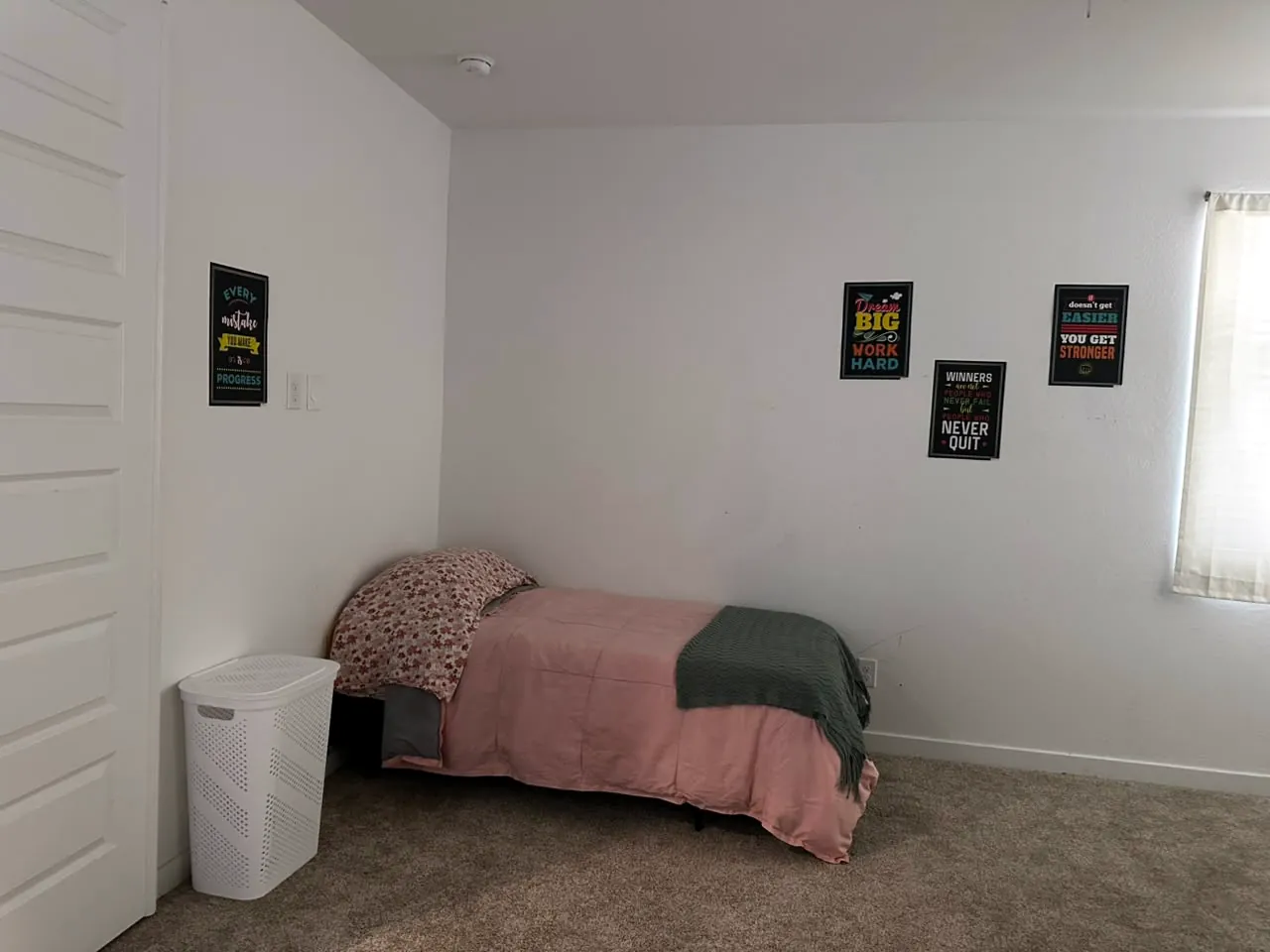Cozy youth bedroom with a pink bedspread and motivational posters