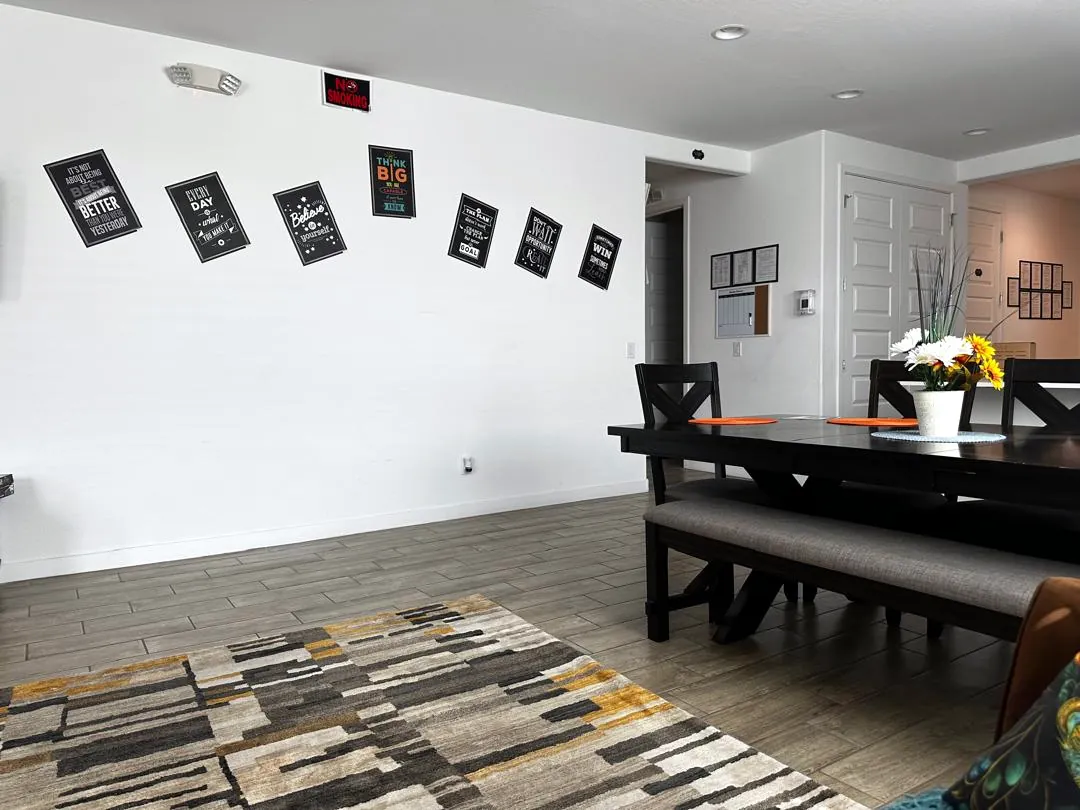 Open dining area with a large wooden table and framed motivational posters on the wall
