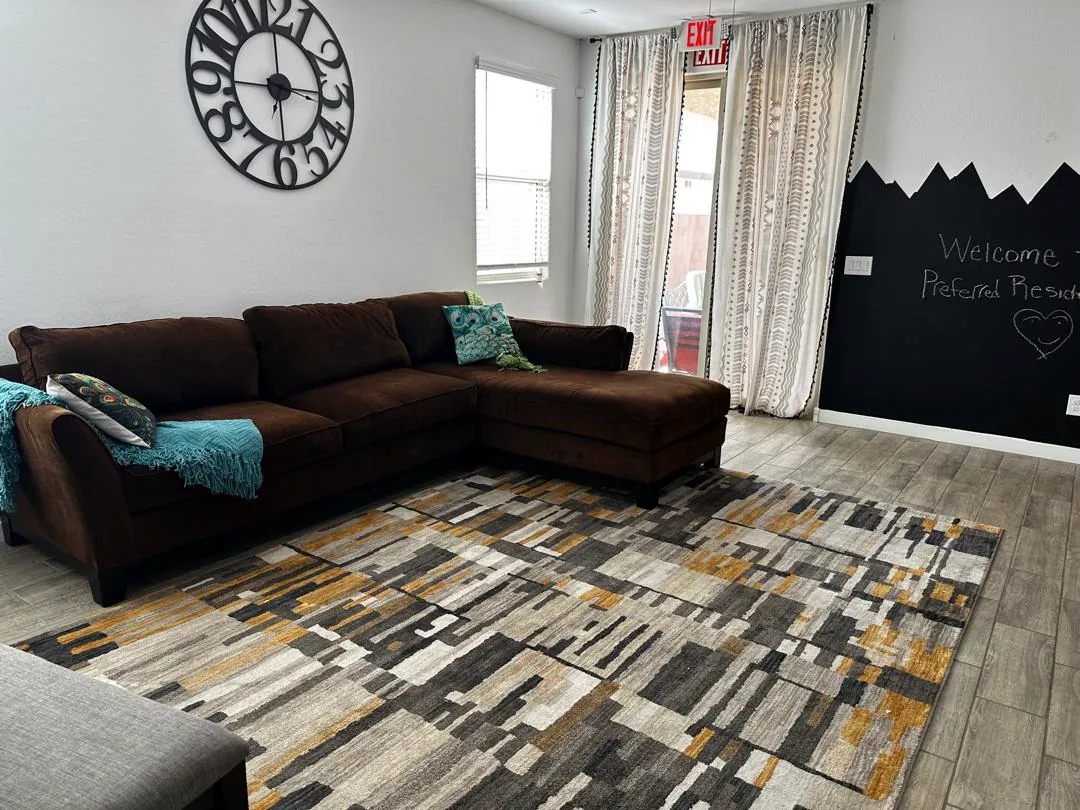 Spacious living room with a large sectional sofa, area rug and natural light