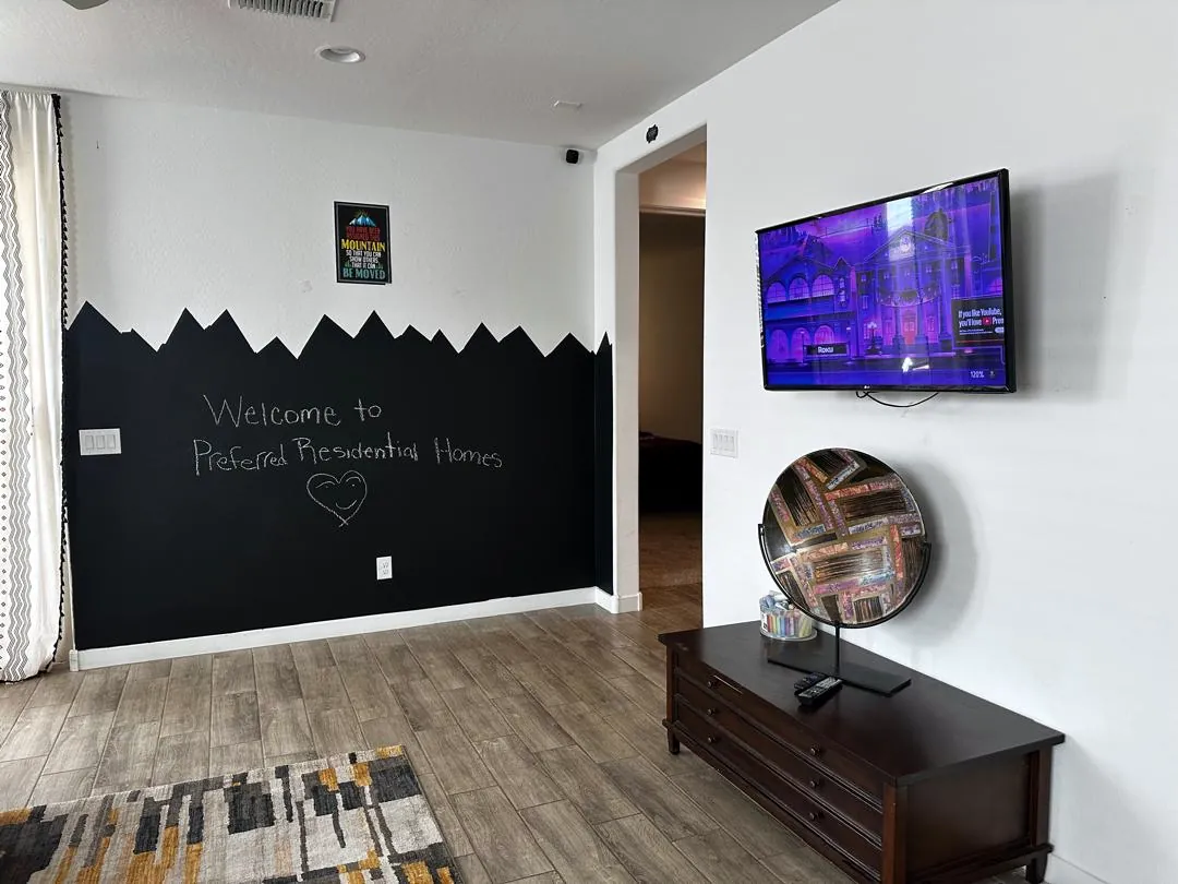 Welcome wall with a hand-written chalkboard greeting in the open living area of Preferred Residential Group Home